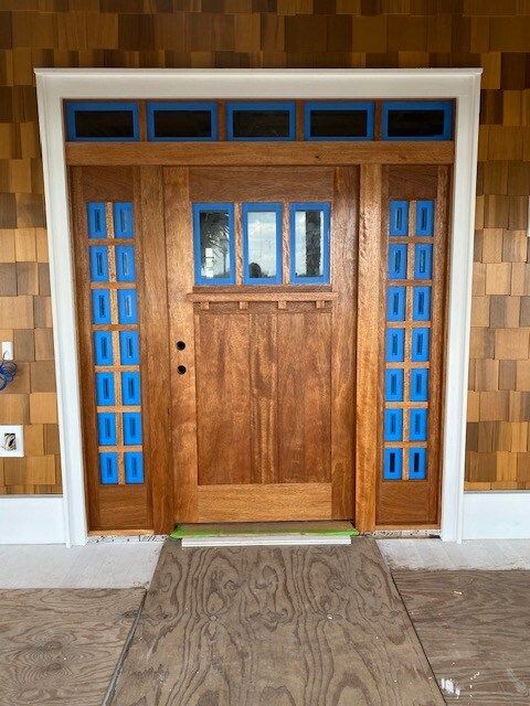A wooden door with blue windows is sitting on a wooden floor.