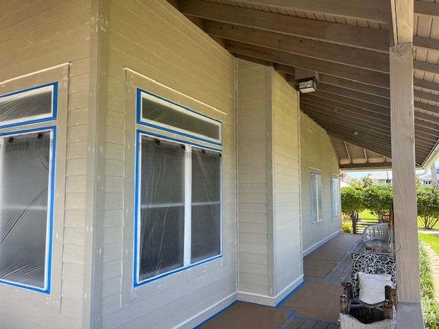 A house is being painted with blue tape on the windows.