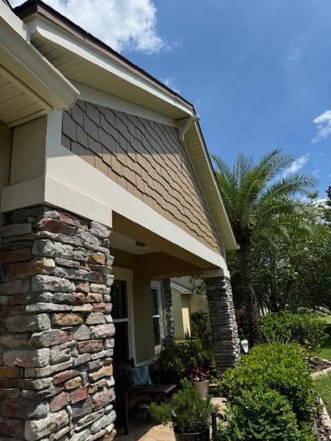 A house with a stone porch and a palm tree in the background
