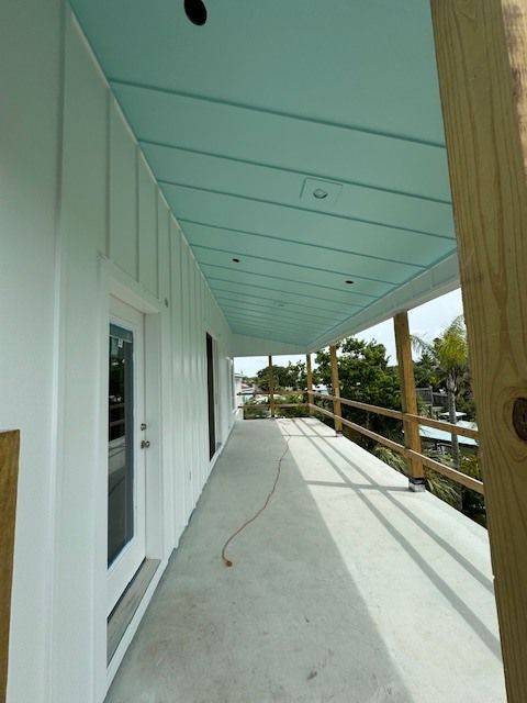 A white house with a blue ceiling and a wooden railing