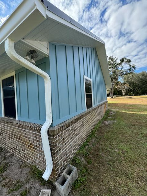 A blue house with a white gutter on the side of it