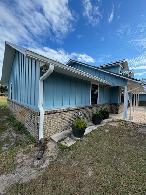 A blue house with a white gutter on the side of it.