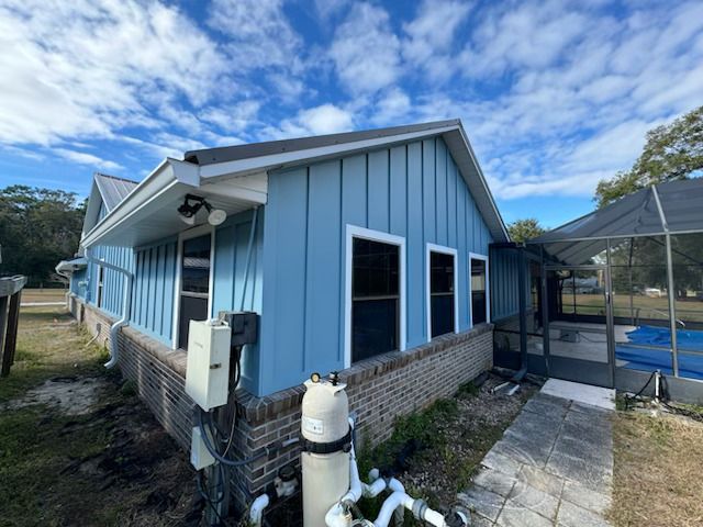 A blue house with a screened in porch and a pool.