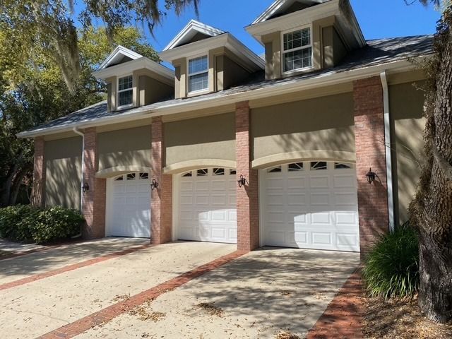 A house with three garage doors and a tree in front of it