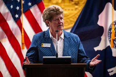 Woman speaking at a podium with American and Wyoming flags behind her.
