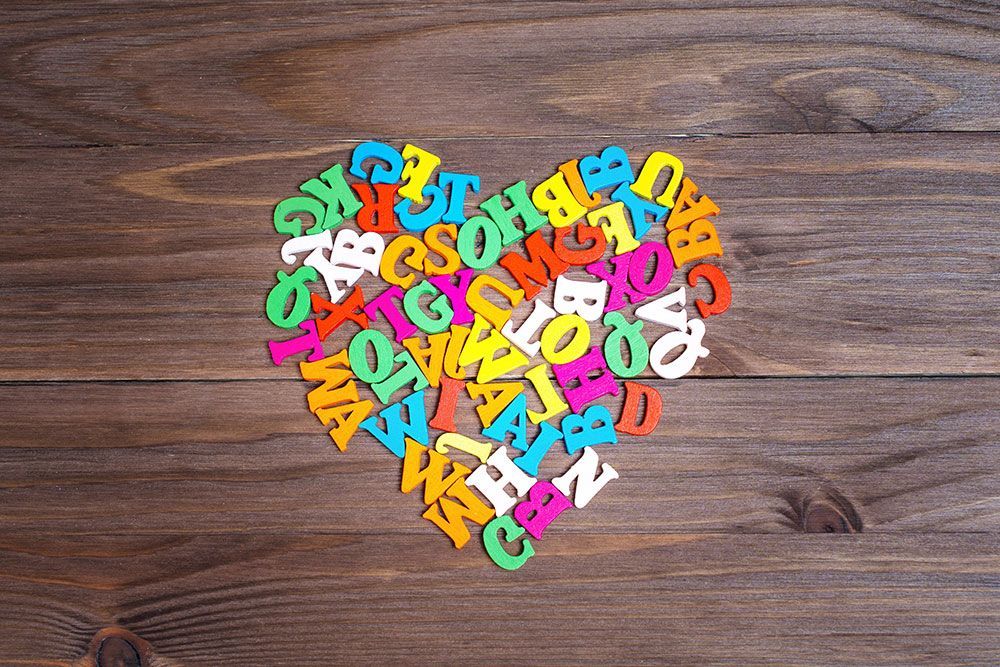 Colorful wooden alphabet letters arranged in a heart shape on a brown wooden surface.