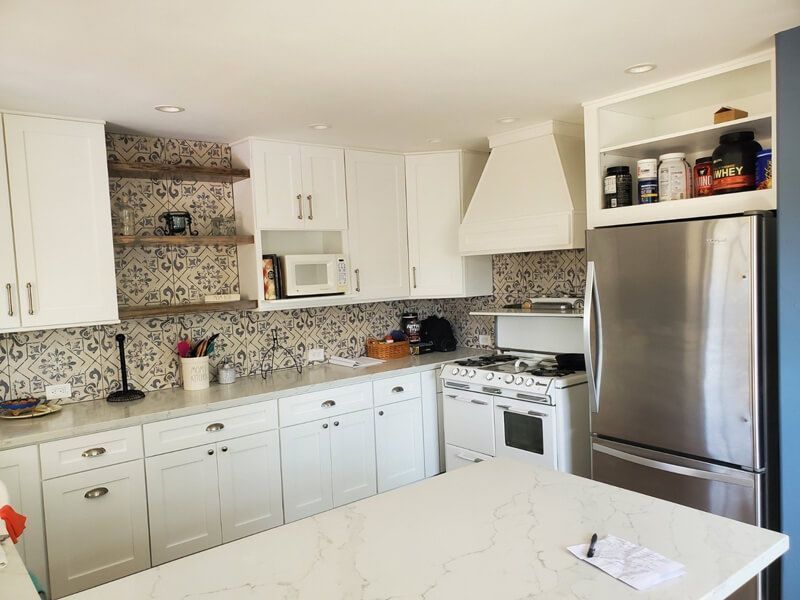A kitchen with white cabinets , stainless steel appliances , a stove and a refrigerator.