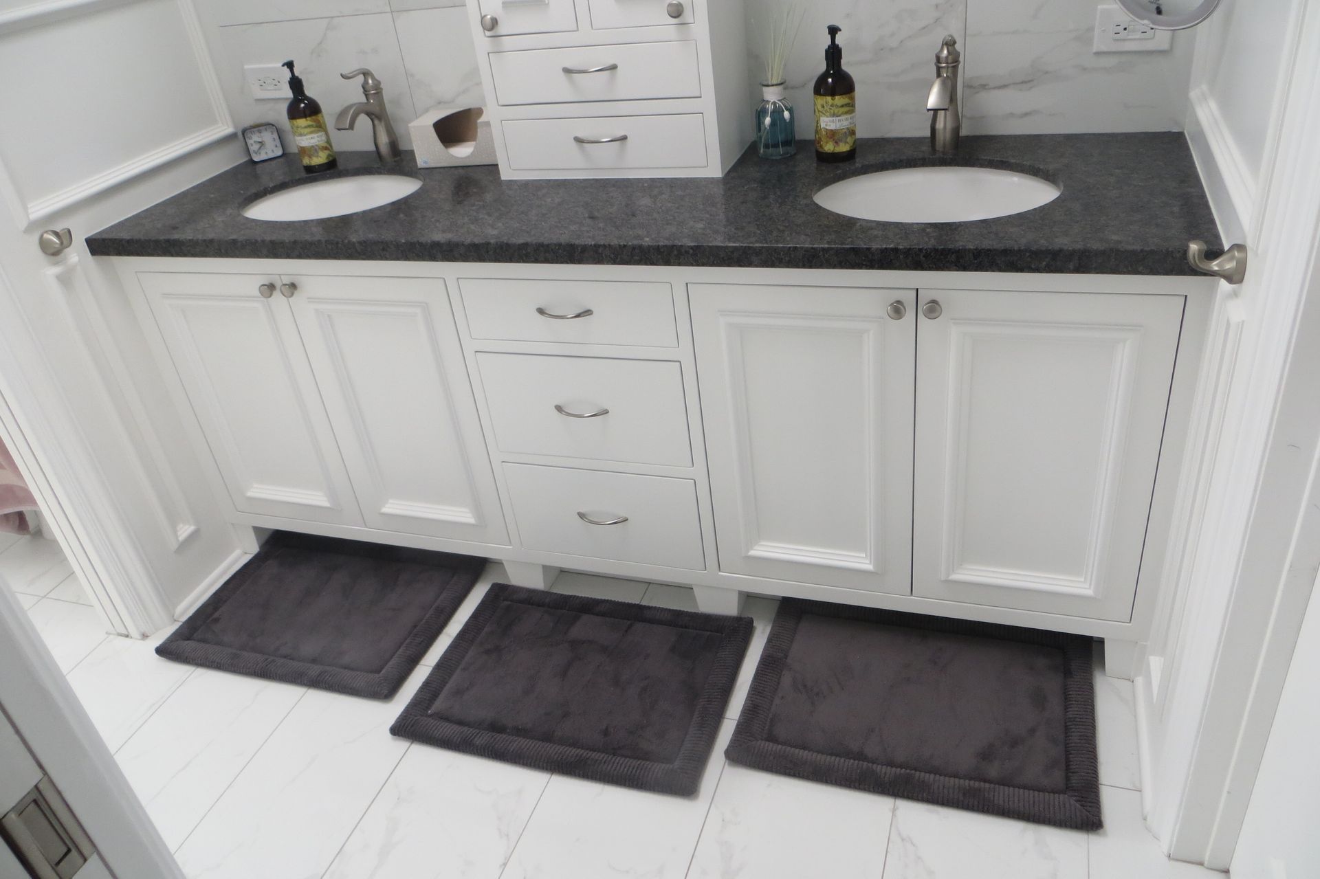 A bathroom with two sinks and three mats on the floor