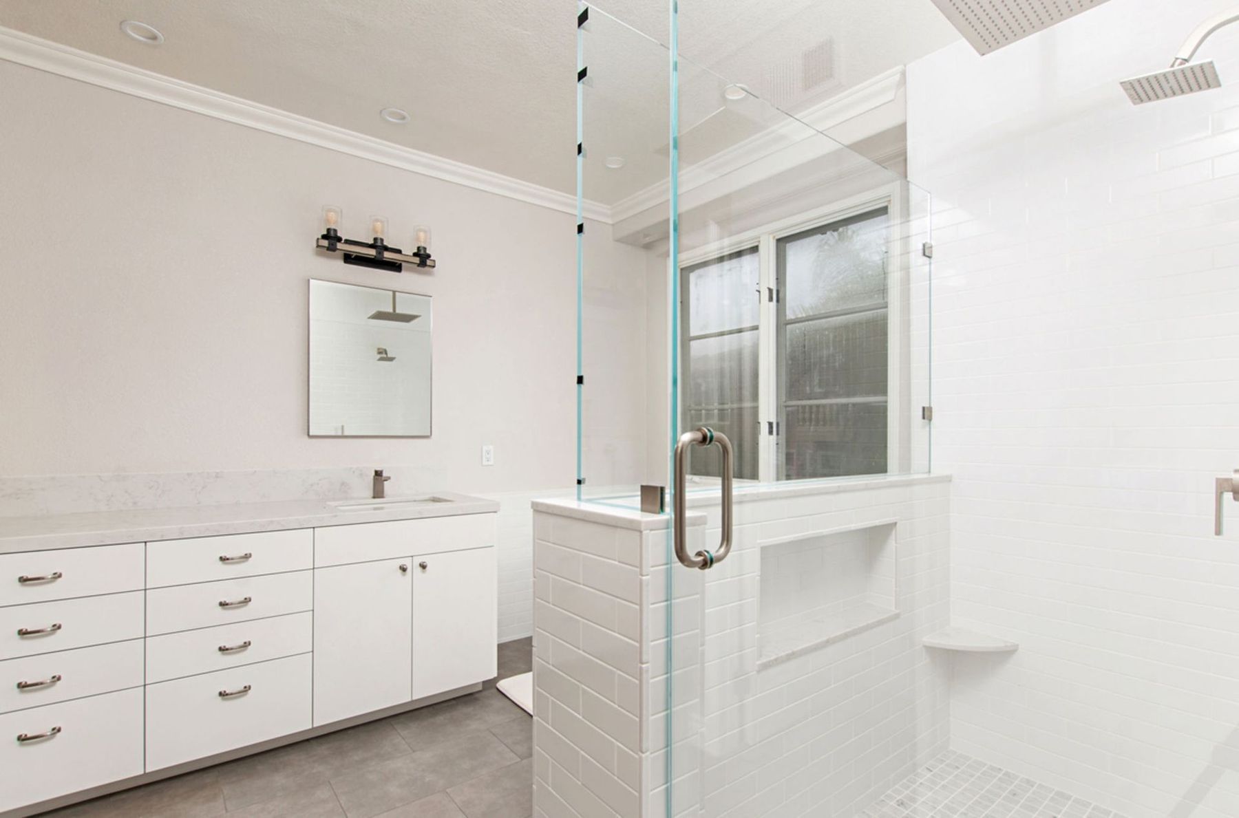 A bathroom with a walk in shower and a sink.