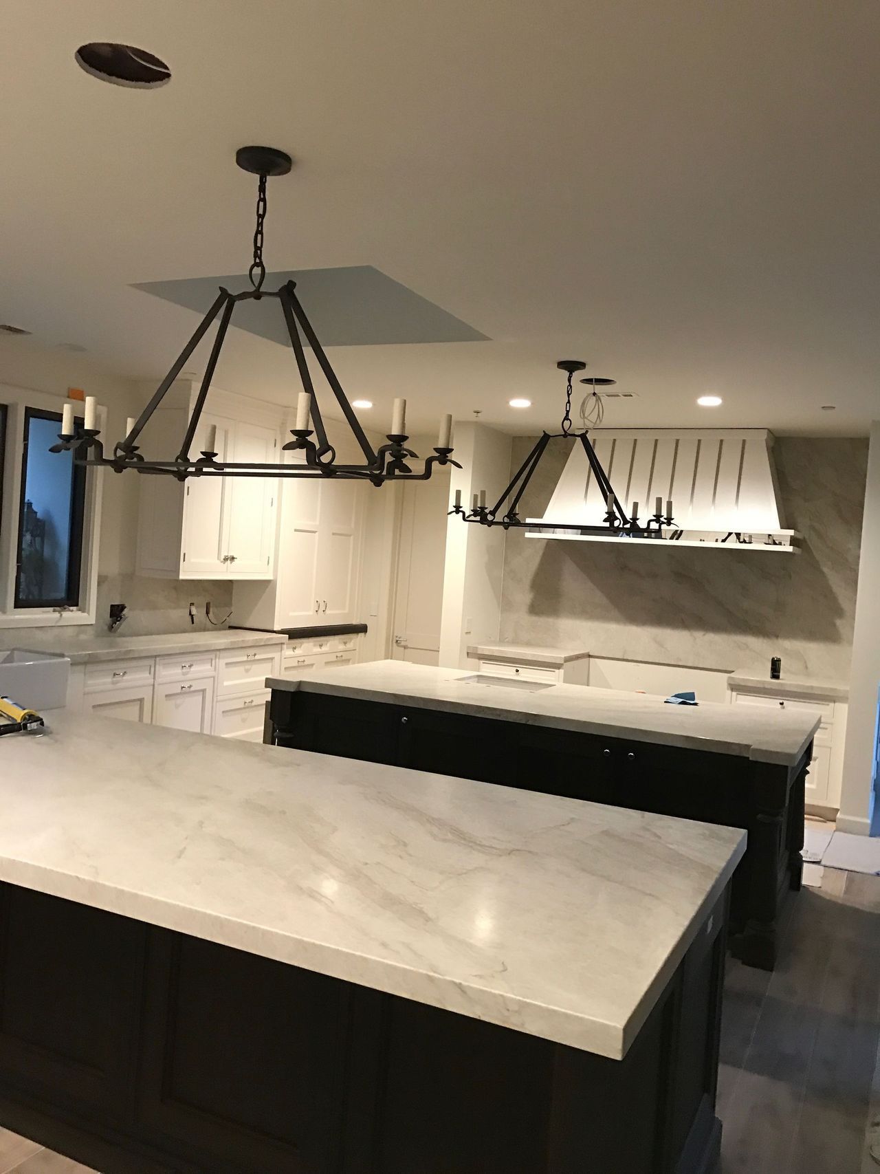 A kitchen with two islands and a chandelier hanging from the ceiling.