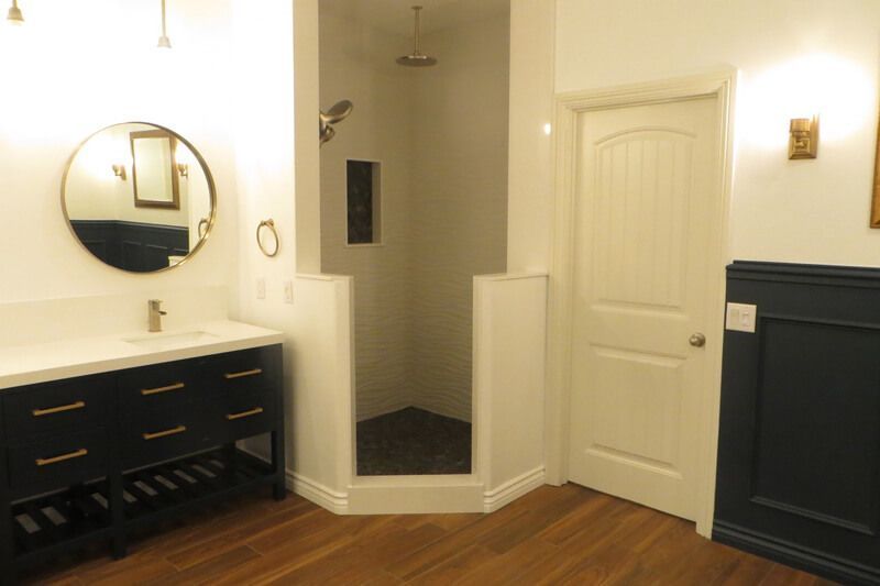 A bathroom with a sink , mirror , and walk in shower.
