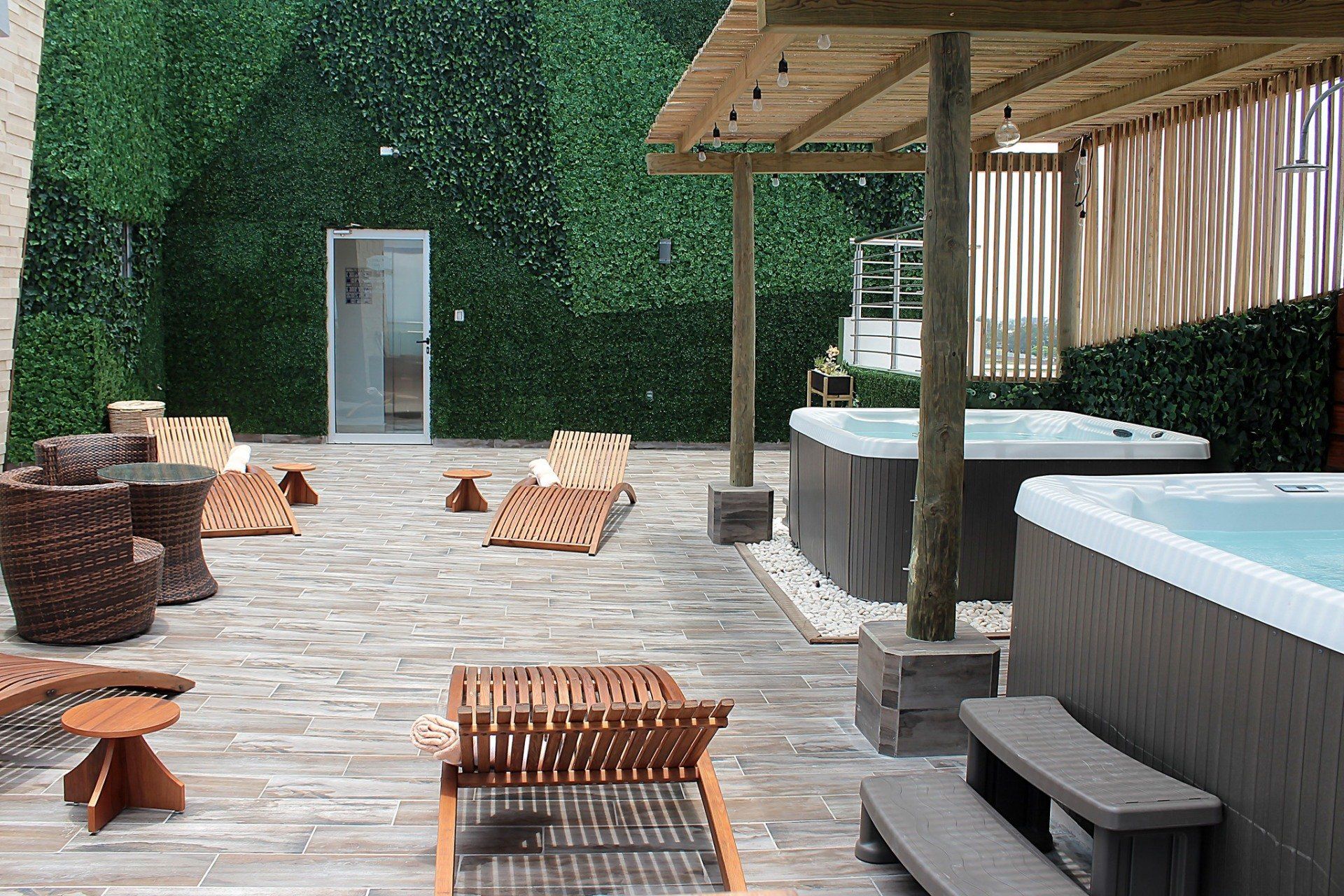 A patio area with two hot tubs and chairs