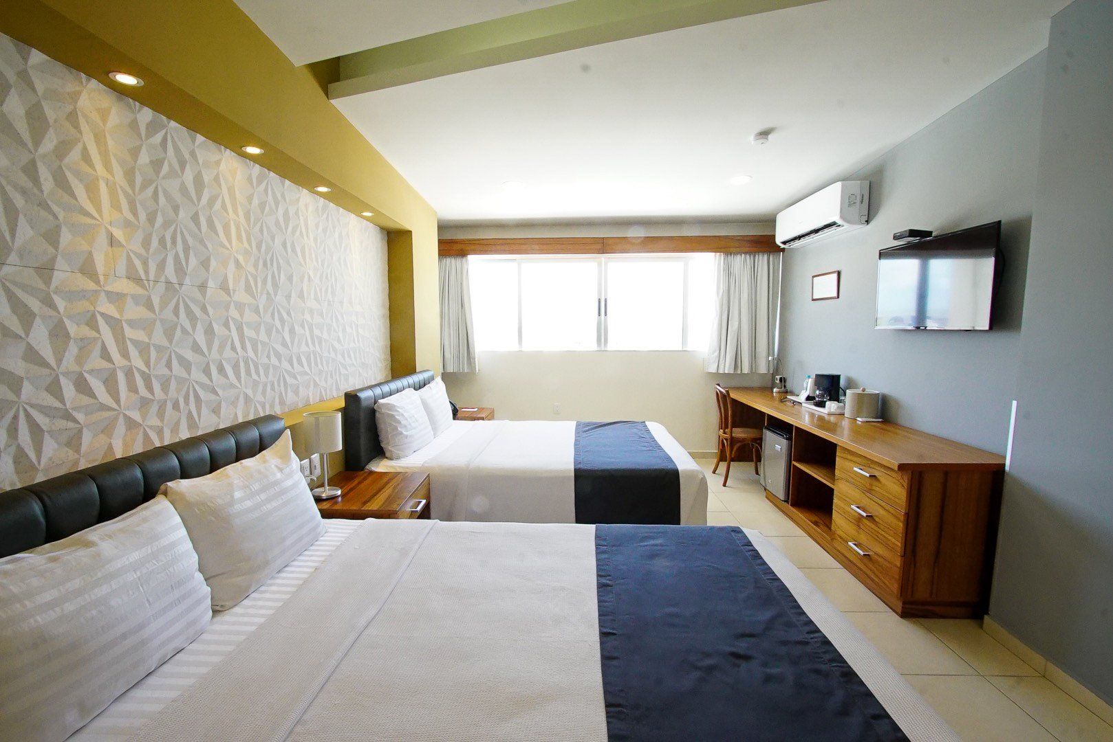 A hotel room with two beds , a desk and a television.