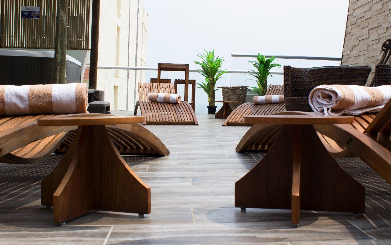 A row of wooden lounge chairs with towels on them.