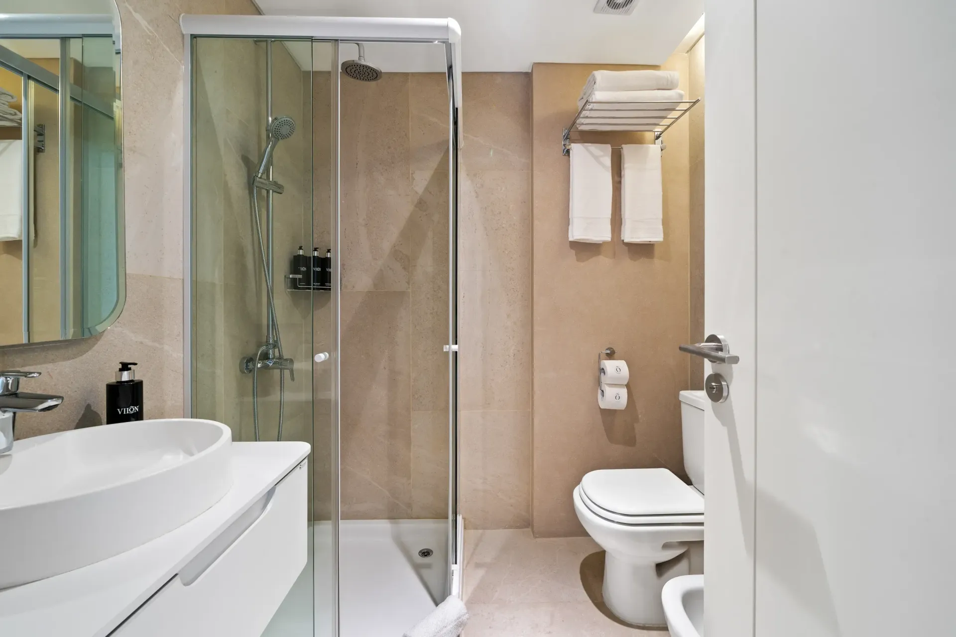 Un baño con inodoro, lavabo, espejo y cabina de ducha.