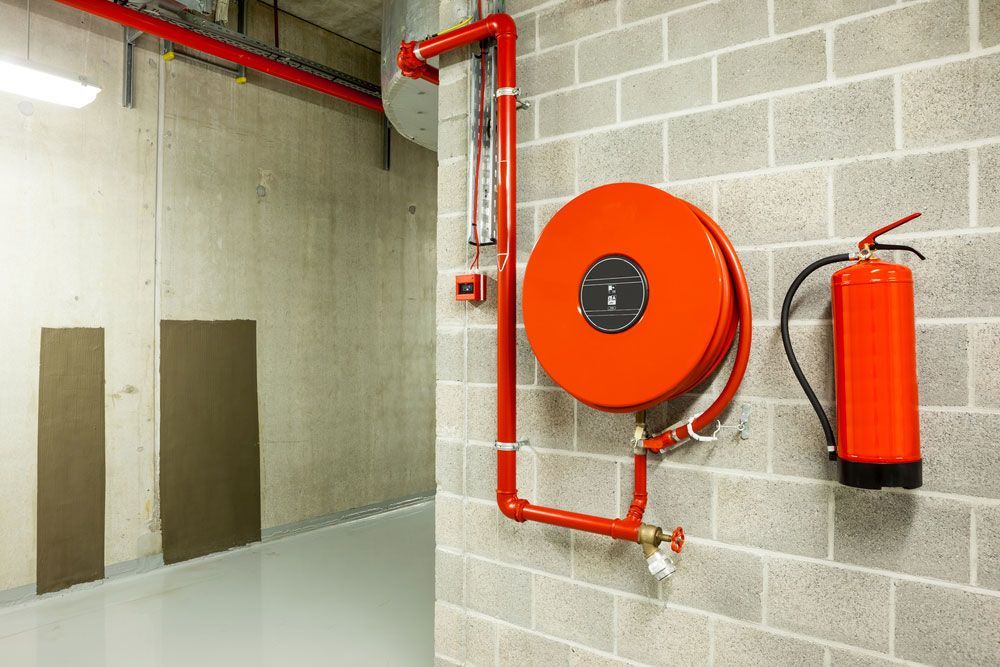 Red Fire Hose Secured to Brick Wall Adjacent to Fire Extinguisher - Hunter Valley NSW
