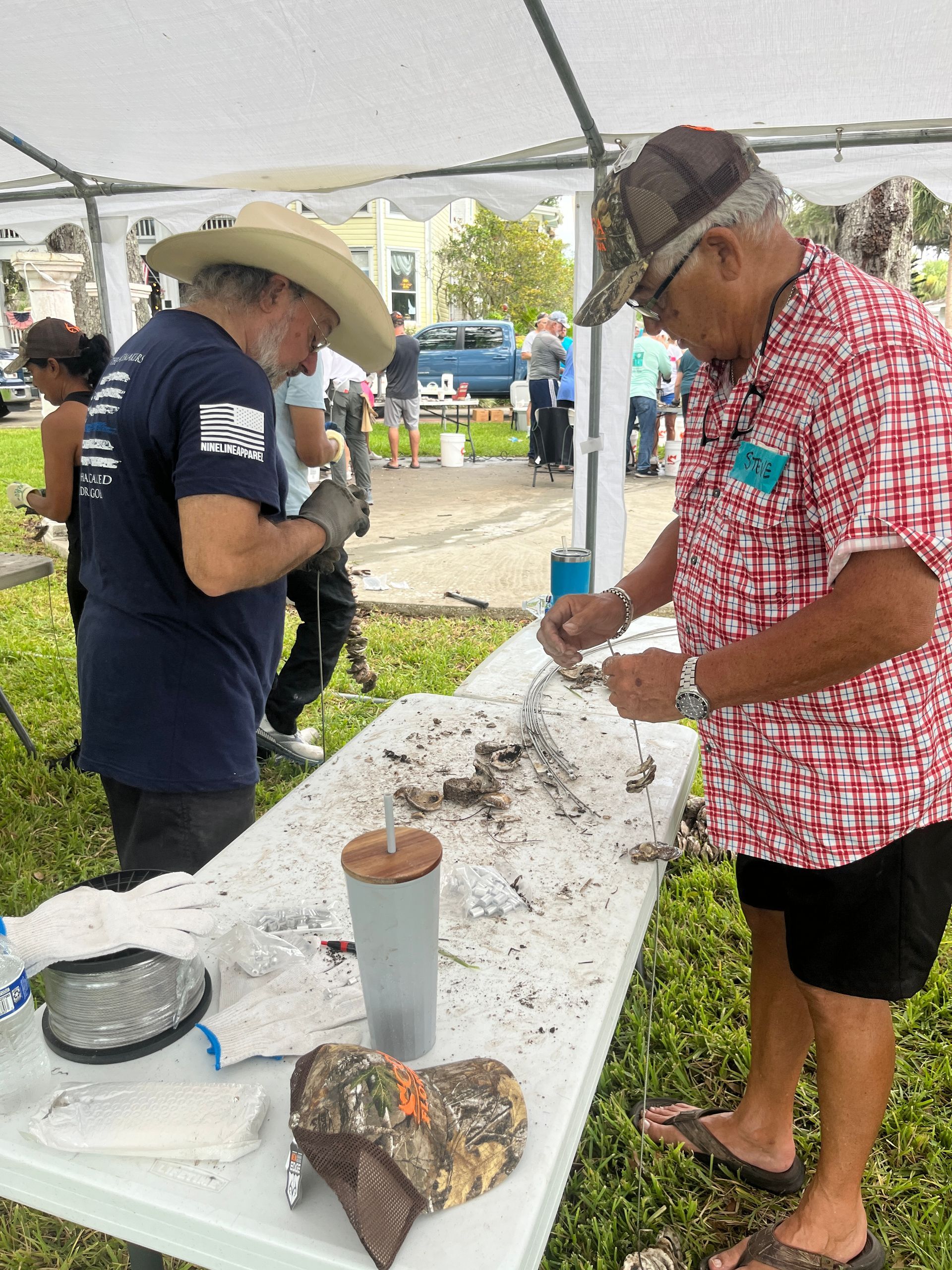 Two men are working on a table under a tent.