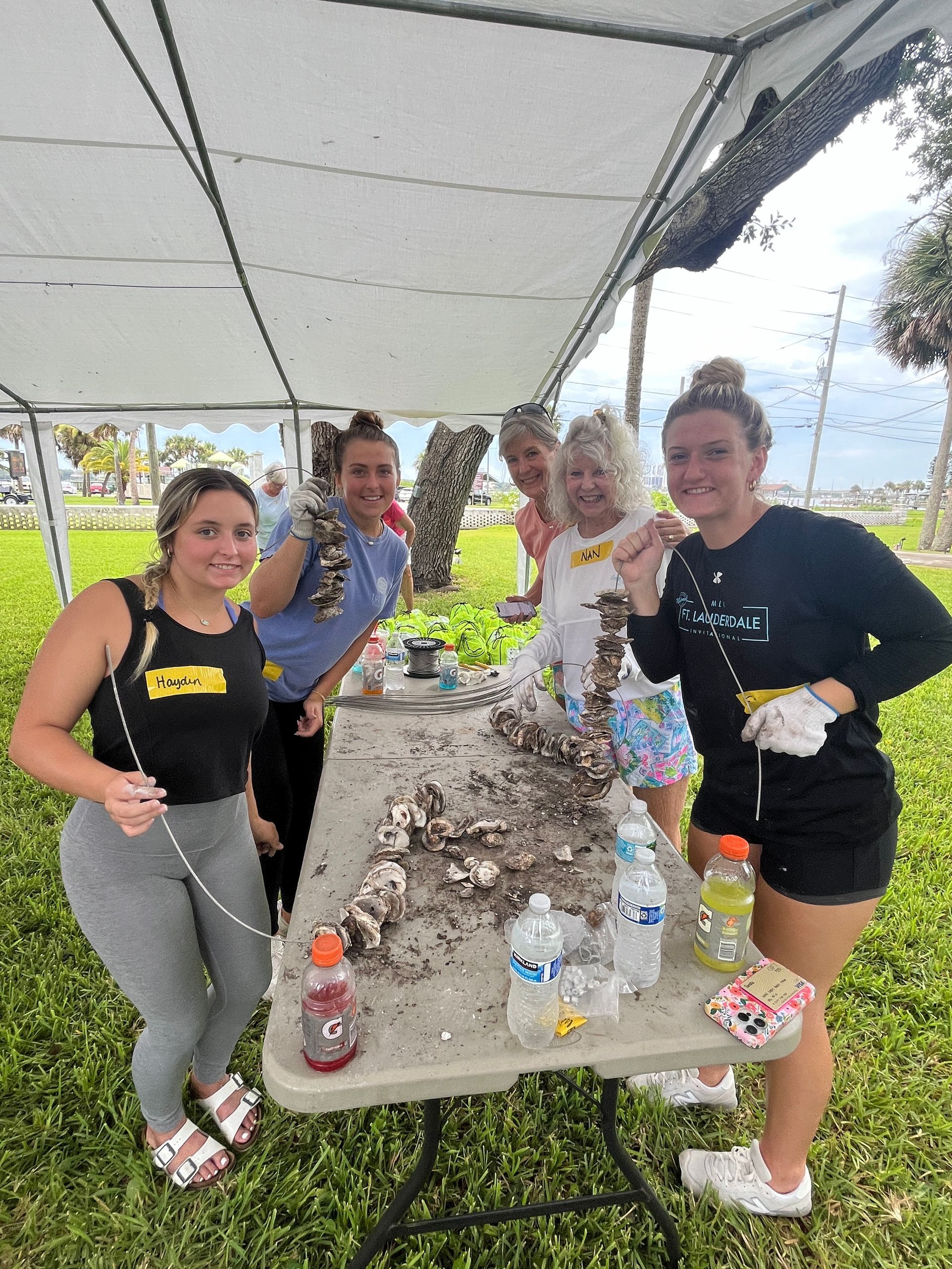 A group of women are standing around a table with oysters on it.