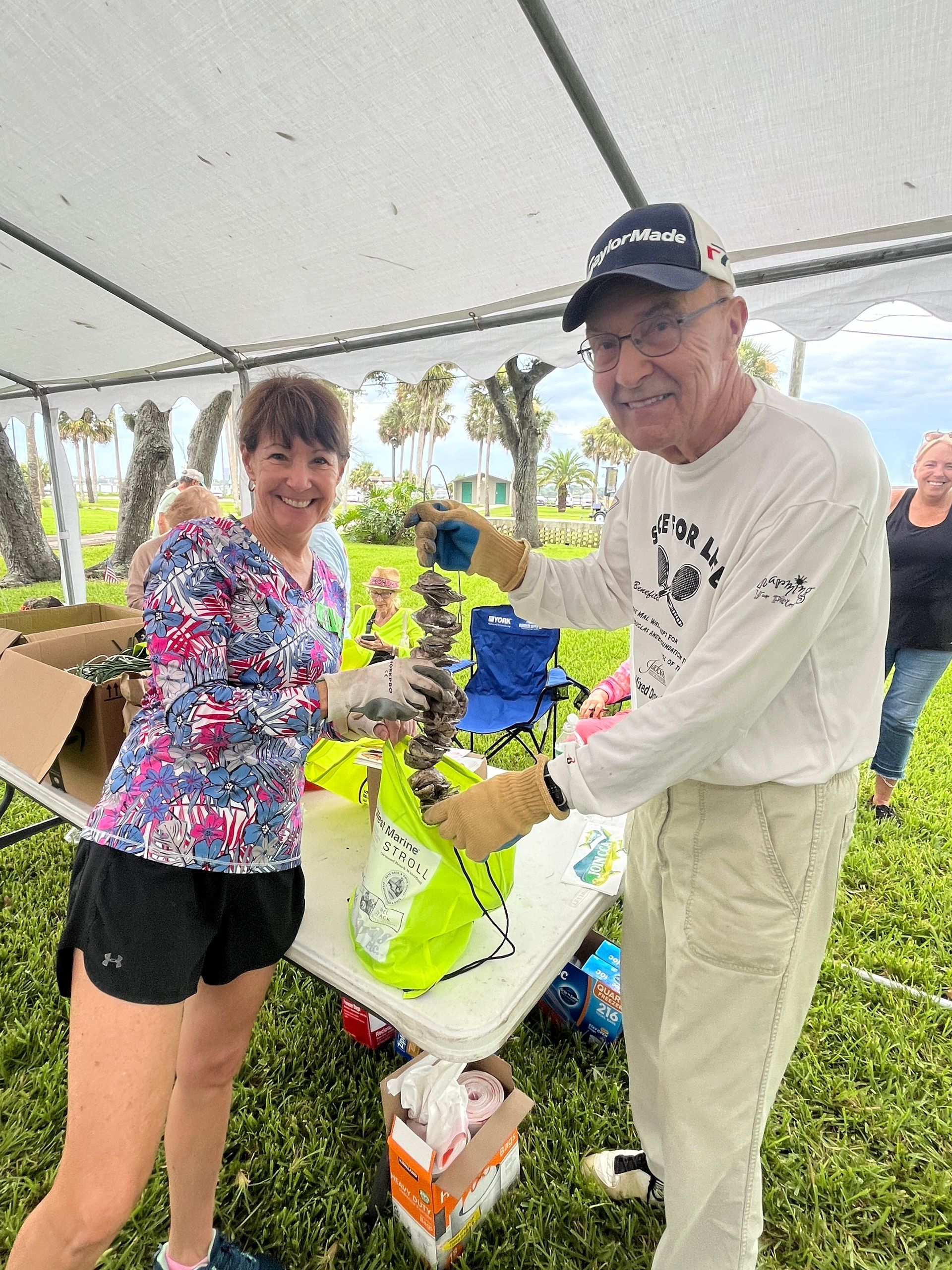 A man and a woman are standing under a tent holding a bird.