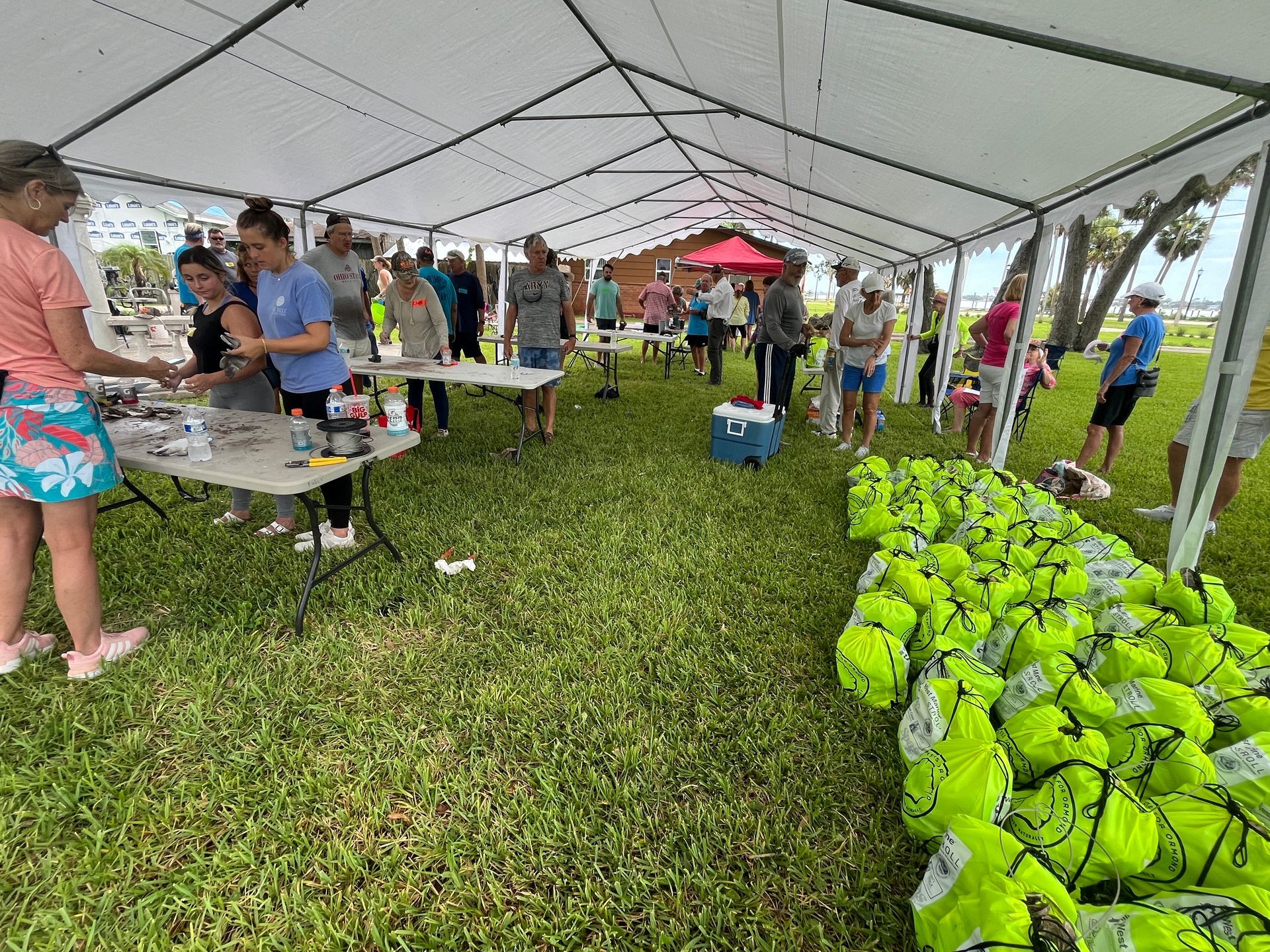 A group of people are standing under a tent in a field.