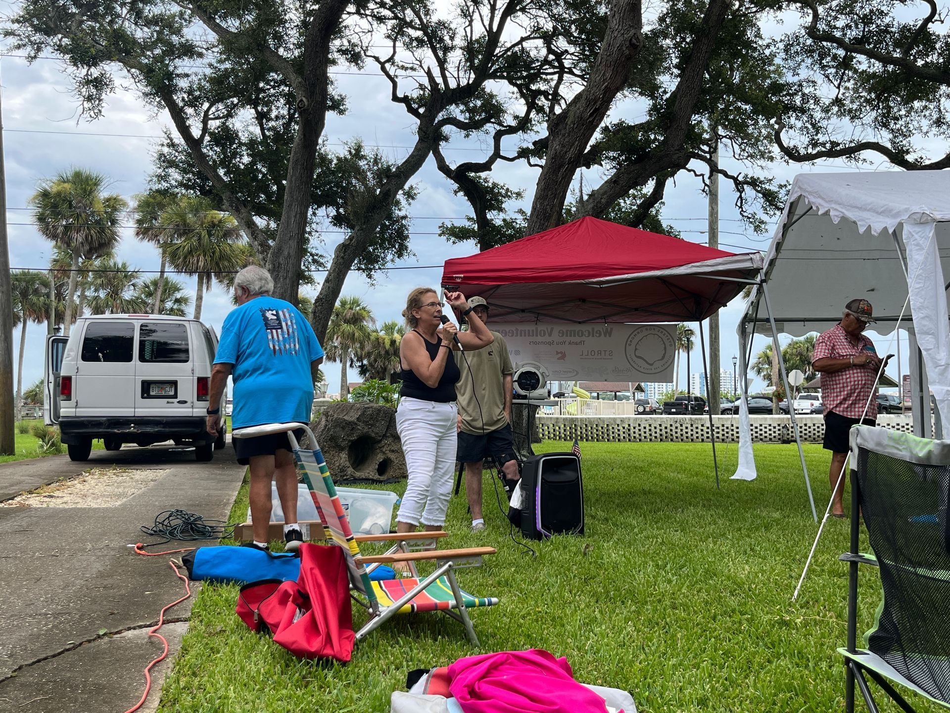 A group of people are standing in front of a tent in a park.