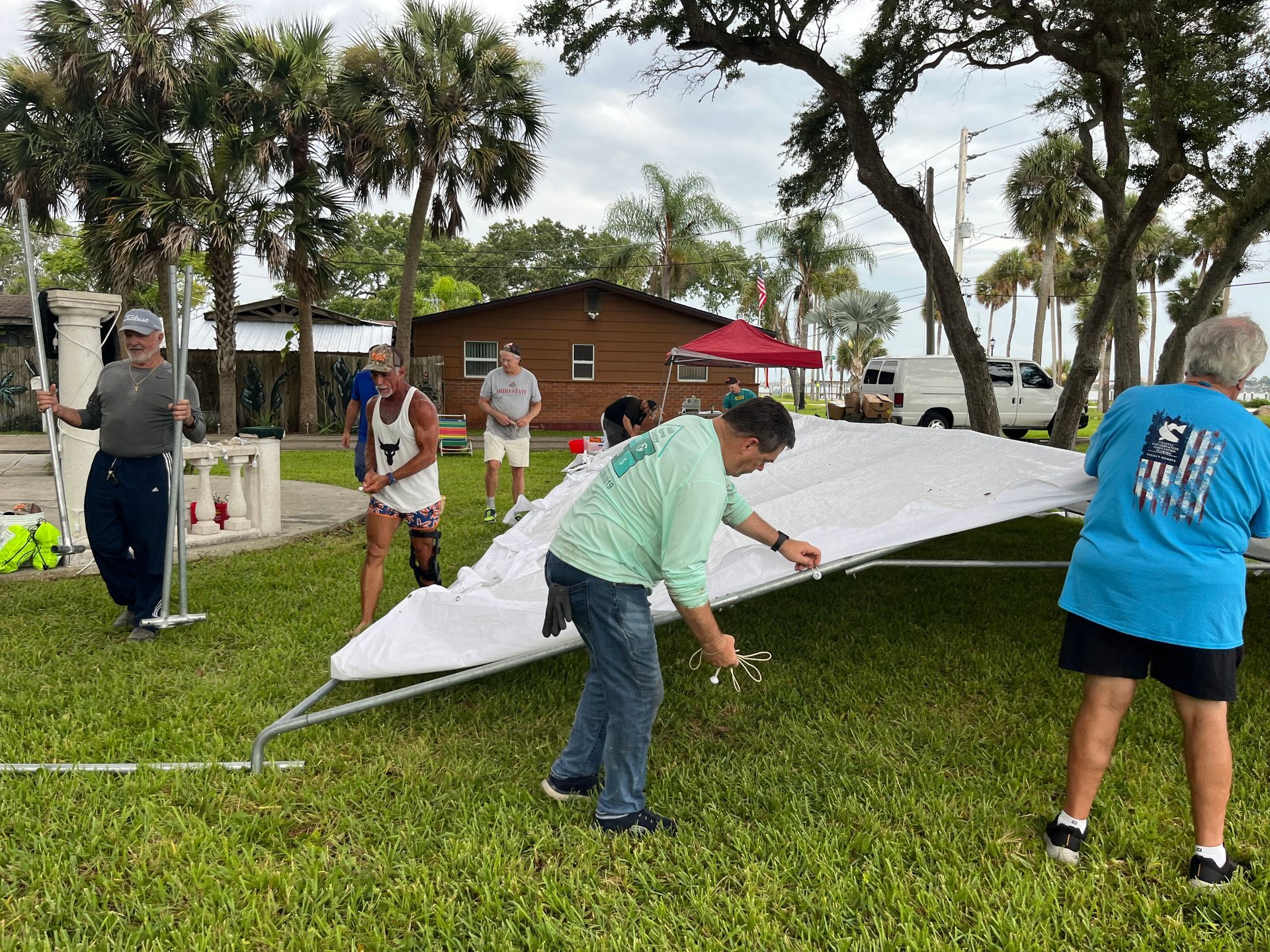 A group of people are setting up a tent in the grass.