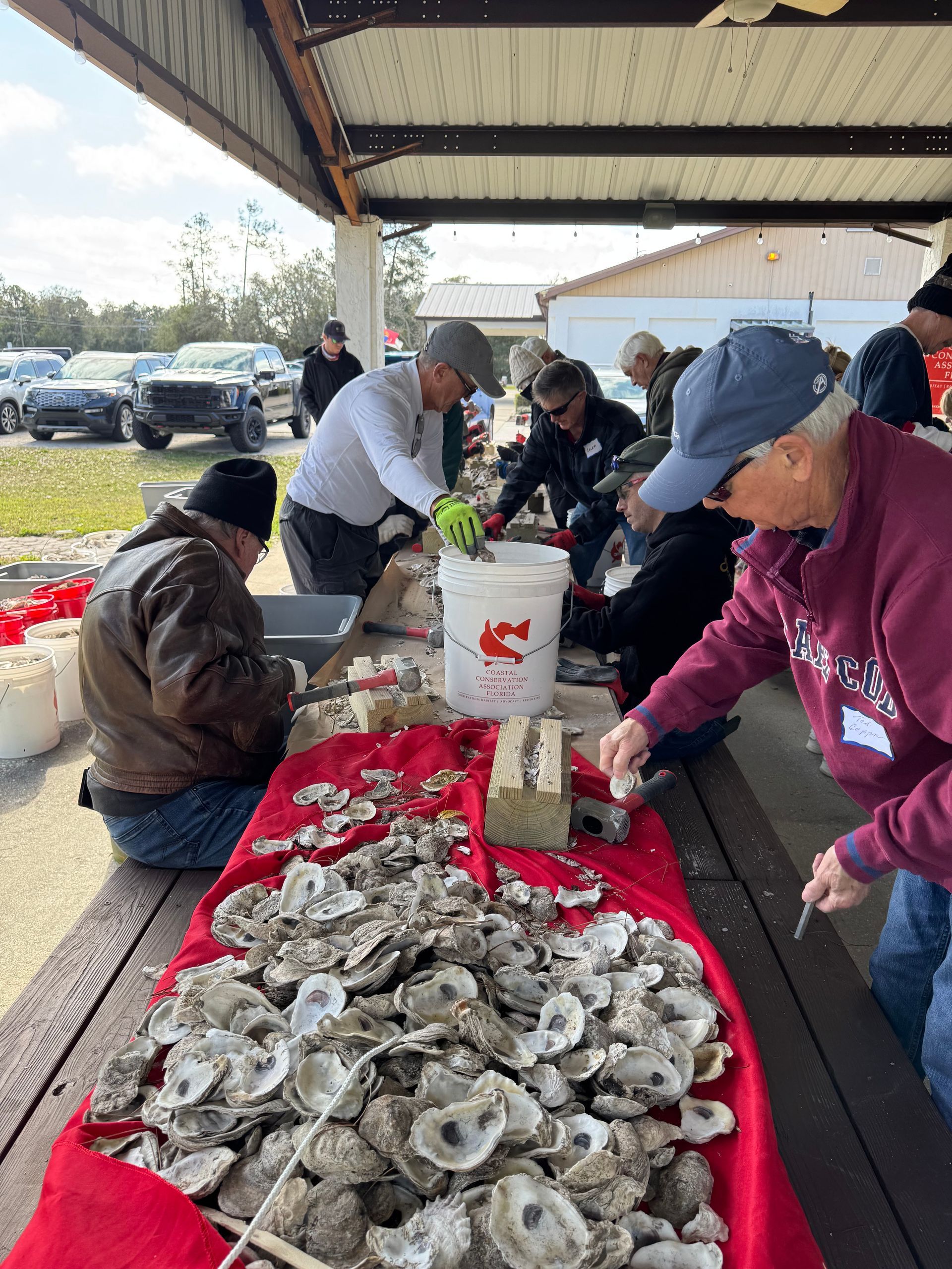 A group of people are gathered around a table filled with oysters.