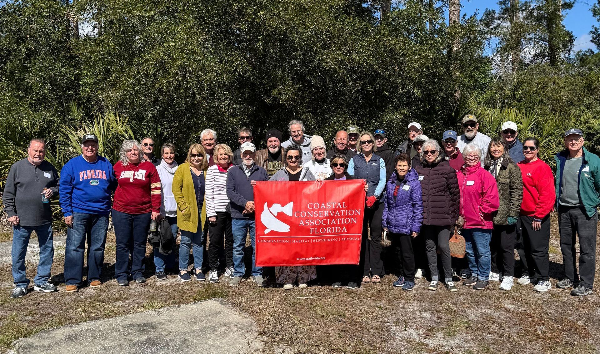 A group of people are standing in a field holding a flag.