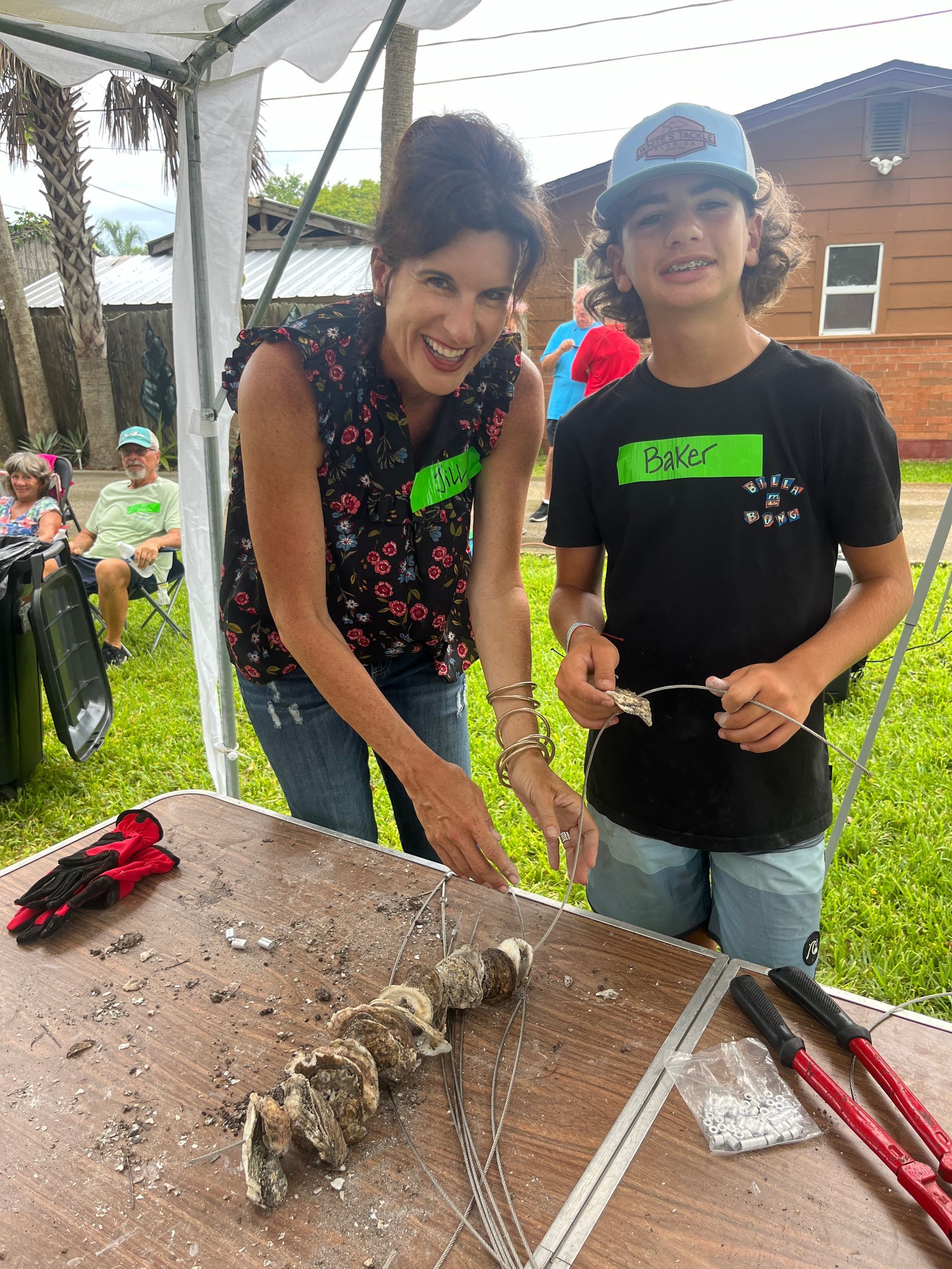 A woman and a boy are looking at oysters on a table.