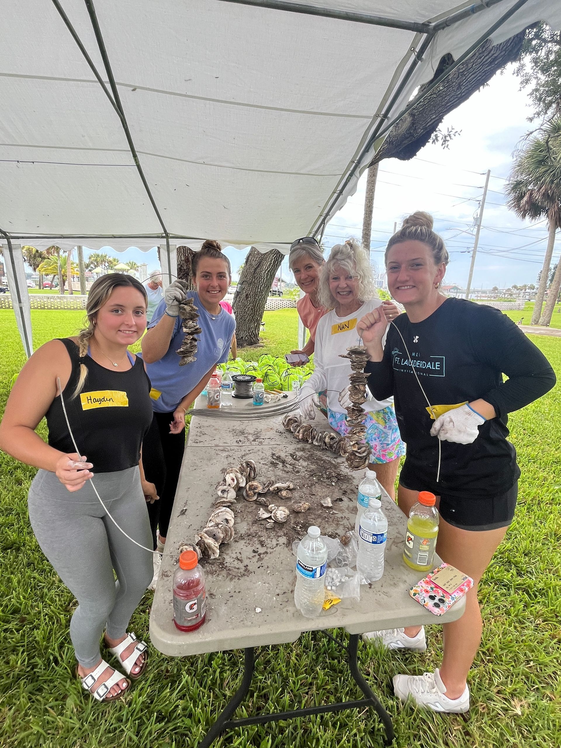 A group of women are standing around a table with oysters on it.