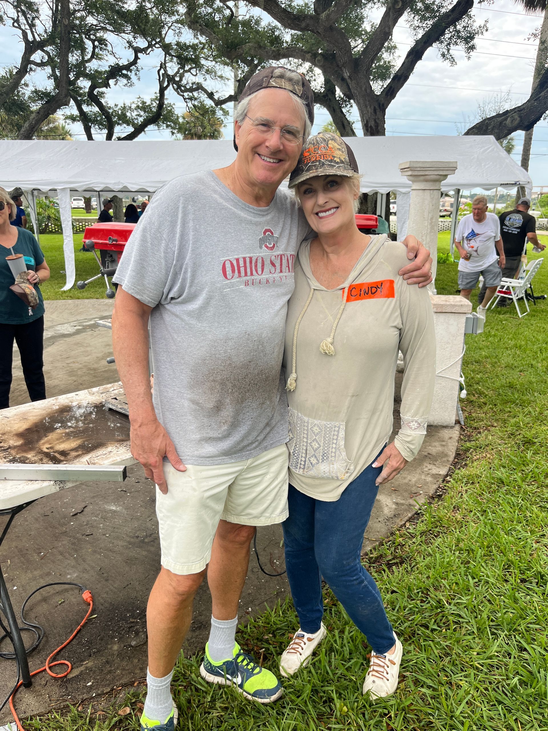 A man and a woman are posing for a picture in a park.