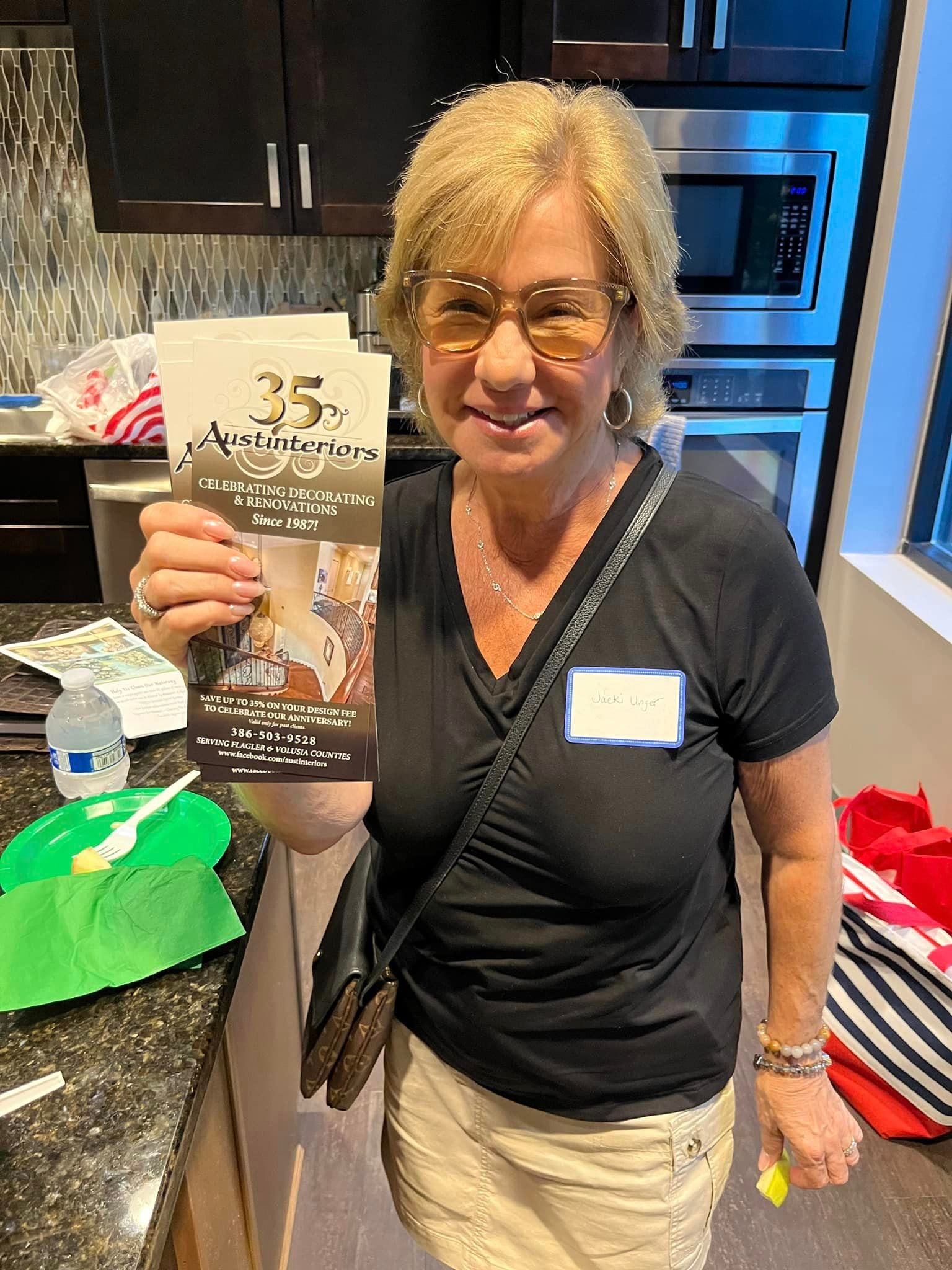 A woman is holding a pamphlet in her hand in a kitchen.