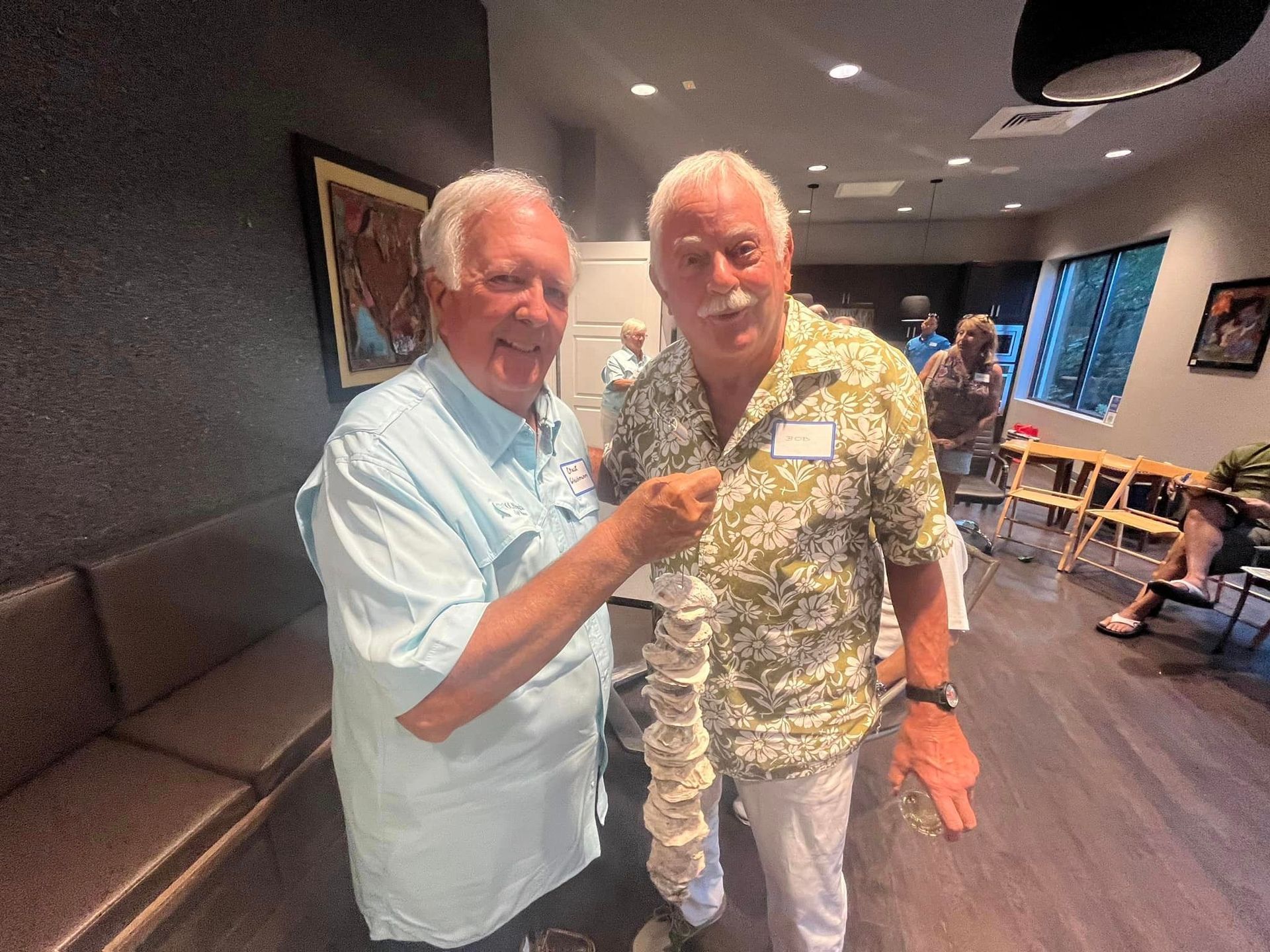 Two men are standing next to each other in a room and shaking hands.