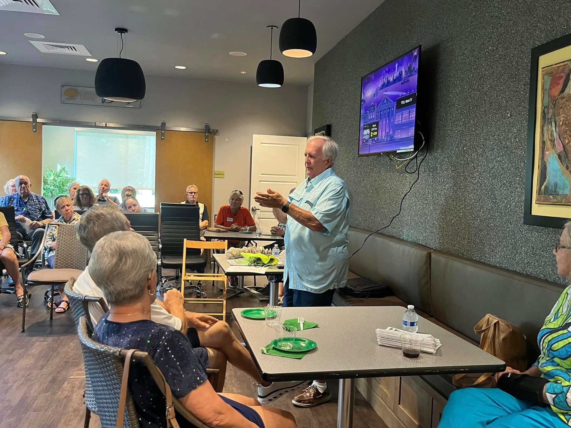 A man is giving a presentation to a group of people sitting at tables.