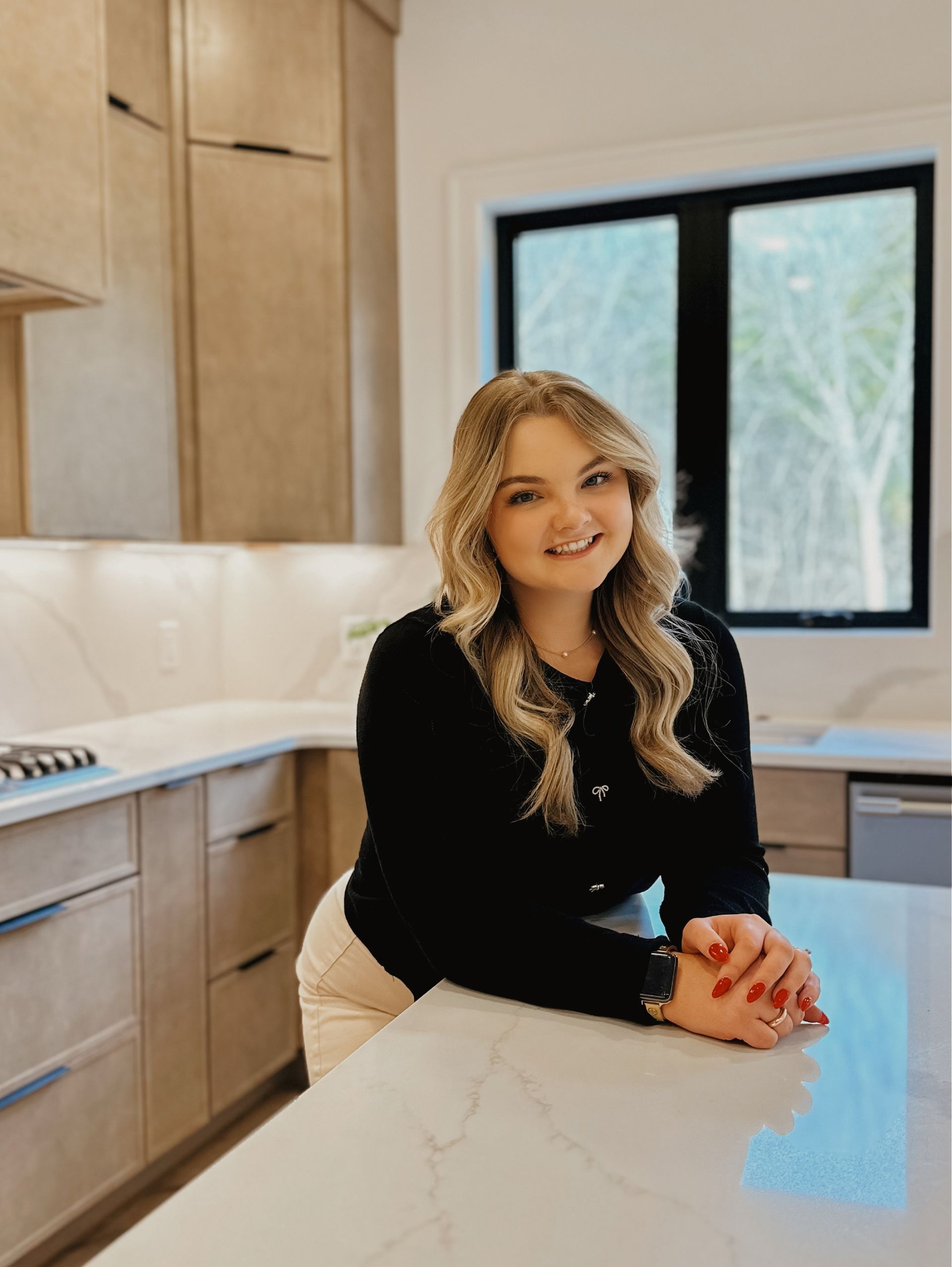 The woman is wearing a white turtleneck and smiling for the camera.
