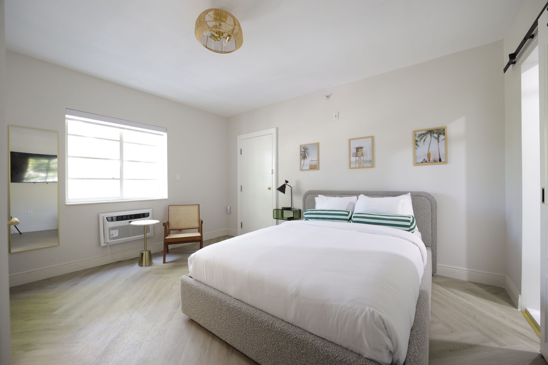 Bedroom with a bed, small side table, chair, and art on the wall. The room is light and airy.