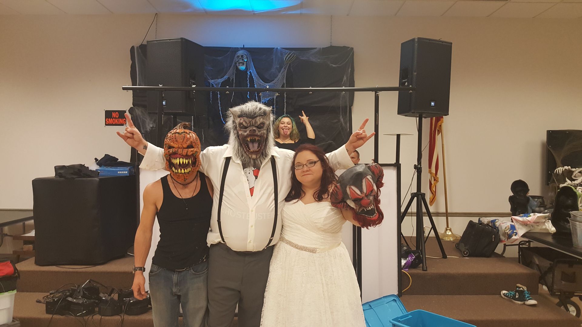 A group of nine people stand together at a party with colorful disco lights and confetti, smiling at the camera.