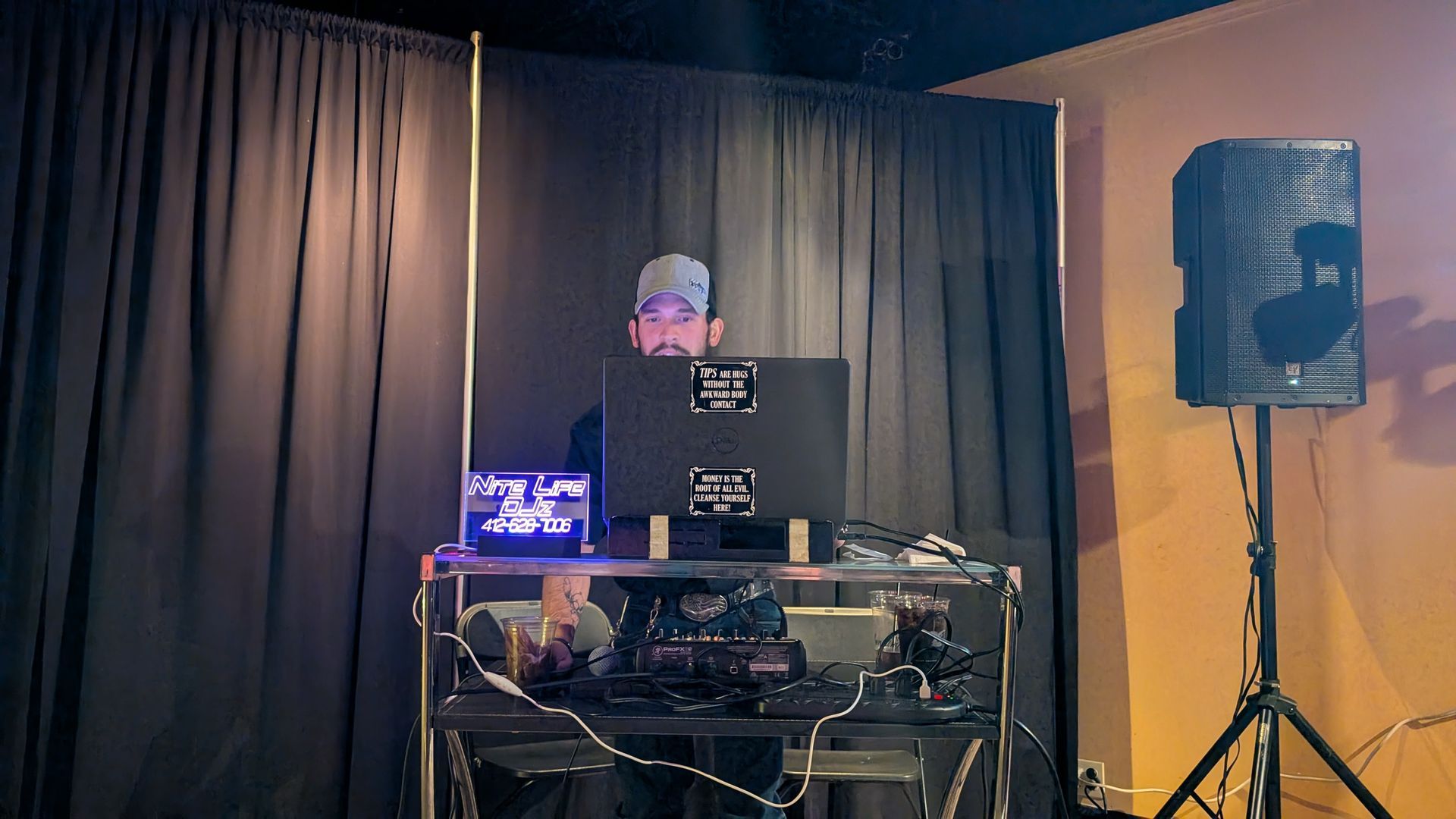 An empty stage set for a performance with colorful lights, white curtains, and a central banner reading