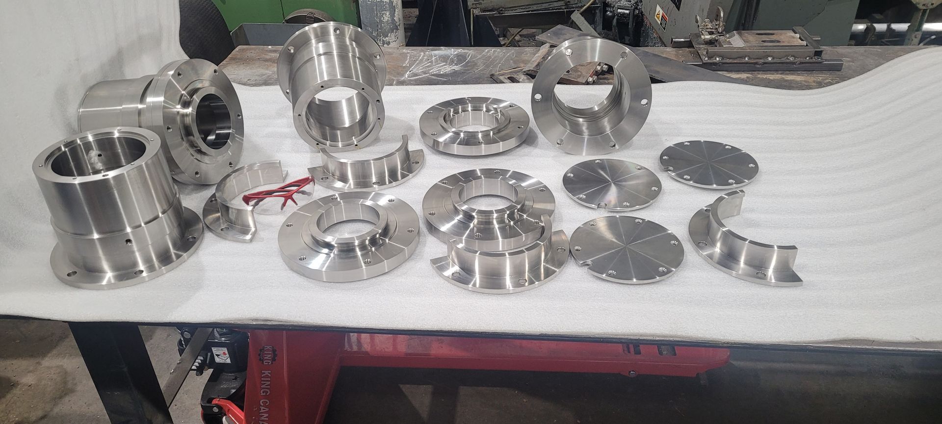 Gros plan sur de nombreuses pièces métalliques brillantes disposées sur une surface blanche.