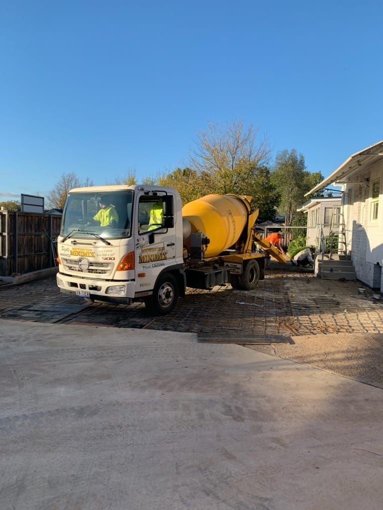 A concrete mixer truck is parked in a parking lot next to a building — Pigot's Midwestern Mini Mix In Orange, NSW