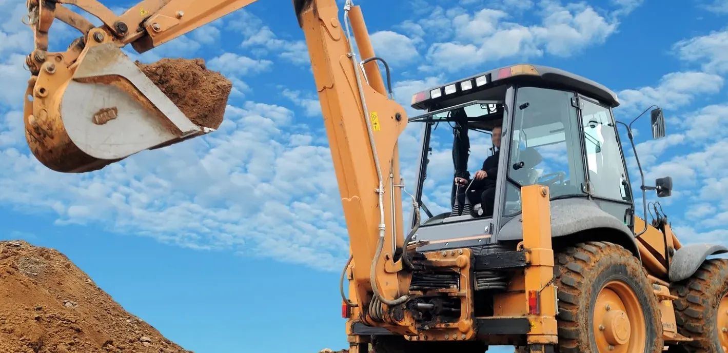 A bulldozer is scooping dirt from a pile of dirt.