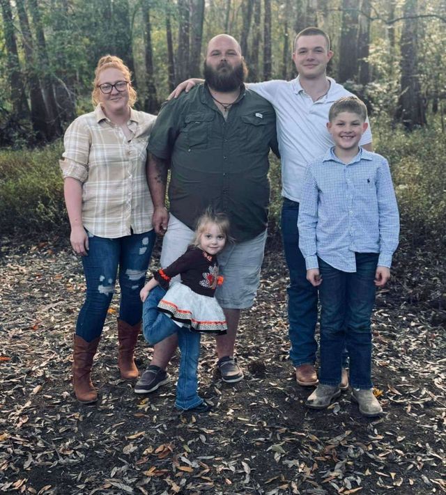 A family posing for a picture in the woods.