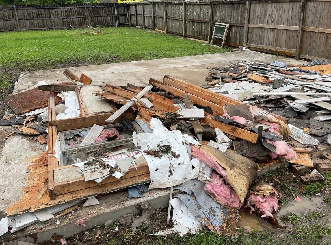 A pile of junk is sitting on the ground in a backyard.