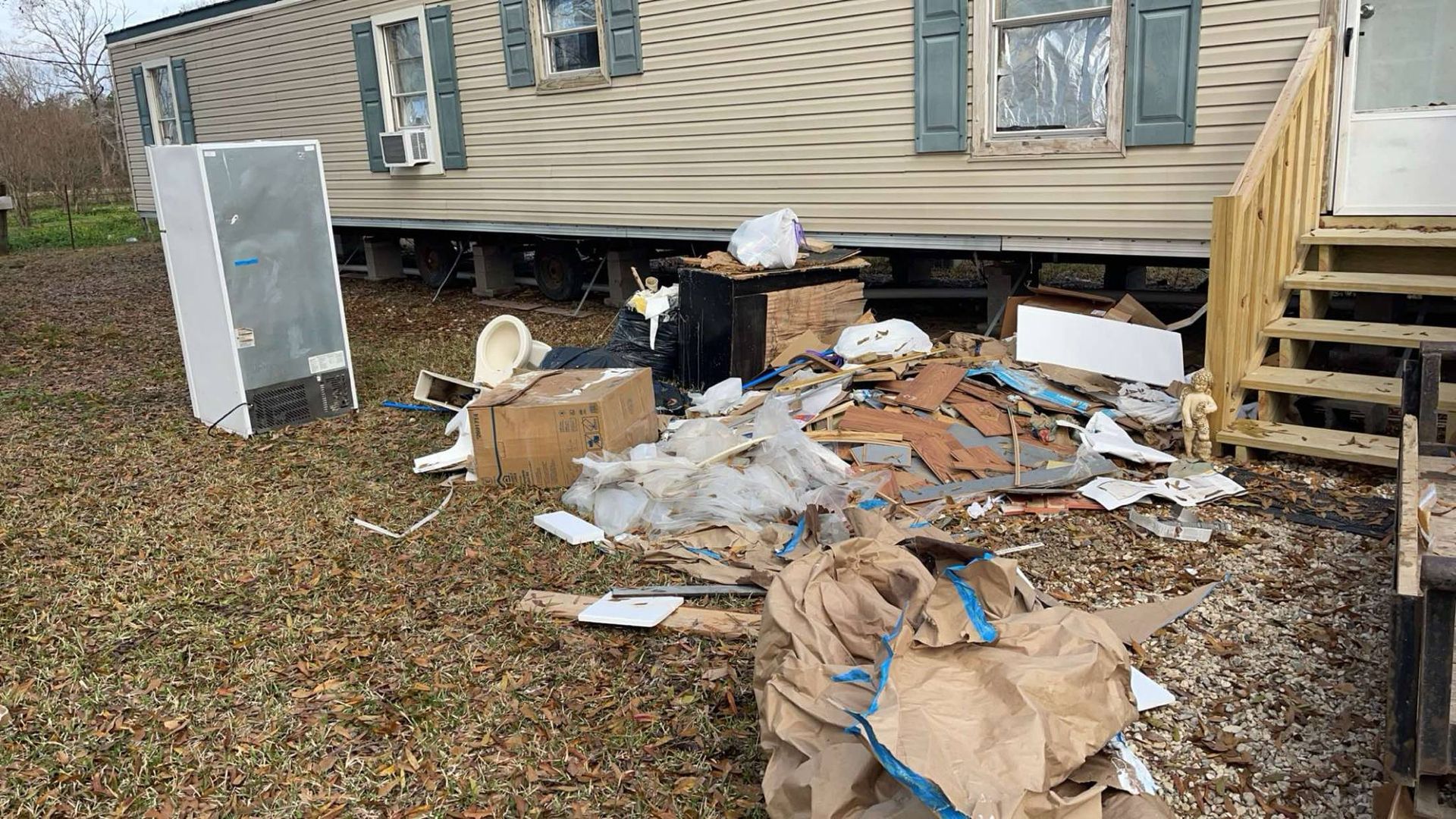A mobile home with a lot of trash in front of it.