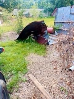 A person is standing in the grass next to a pile of trash.