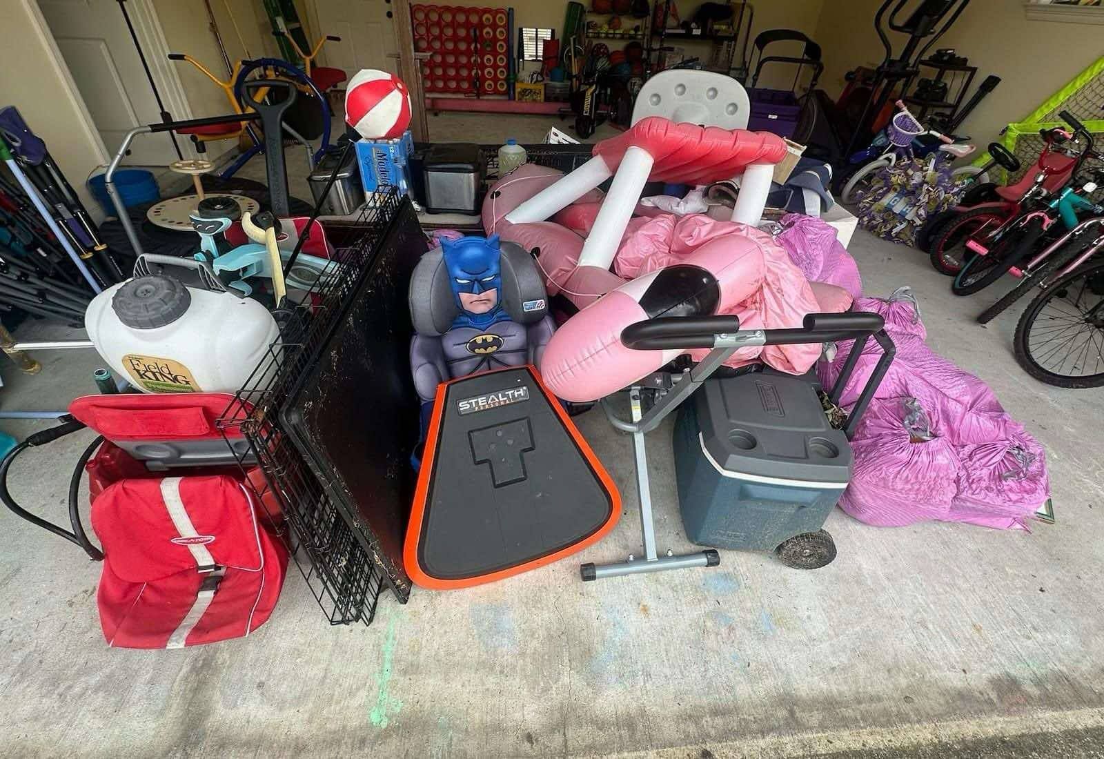 A bunch of stuff is sitting on the ground in a garage.