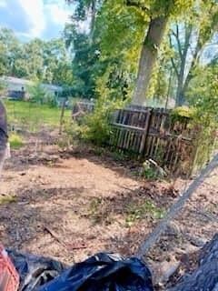 A person is sitting in the dirt next to a tree.