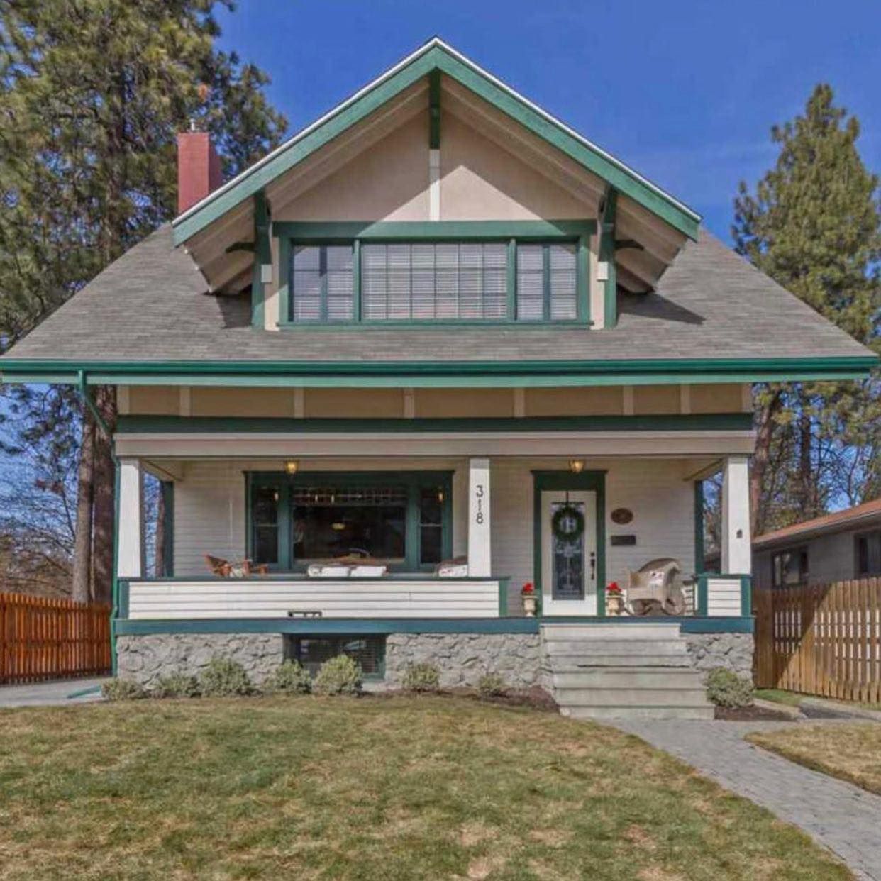 A white house with a green roof and a porch