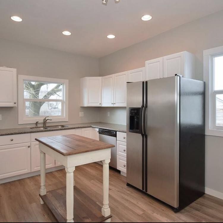 A kitchen with white cabinets and a stainless steel refrigerator