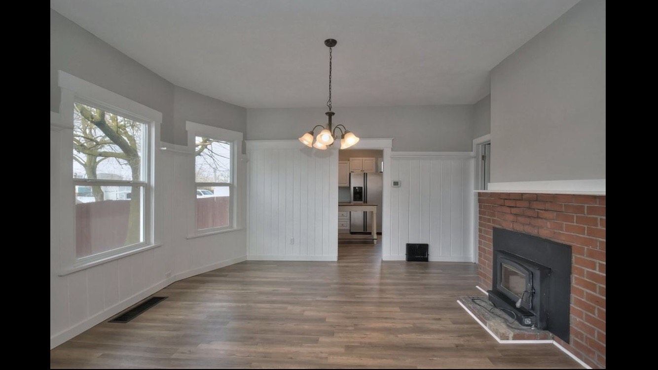 An empty living room with a fireplace and a chandelier.
